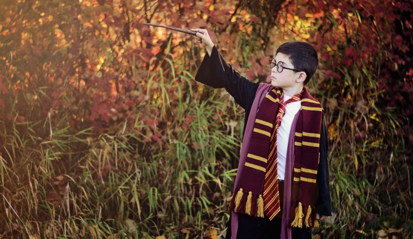 A boy in a harry potter costume is holding a wand.