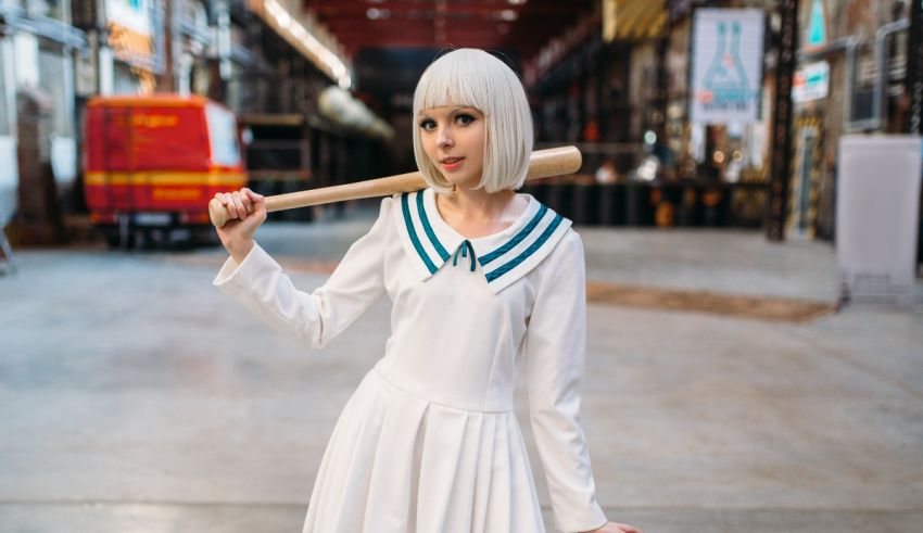 A girl in a white dress holding a baseball bat.