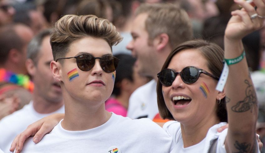 Two people at a pride parade with rainbow painted t - shirts.
