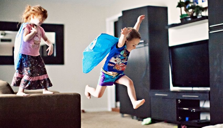 A little girl is jumping in a living room with a tv.