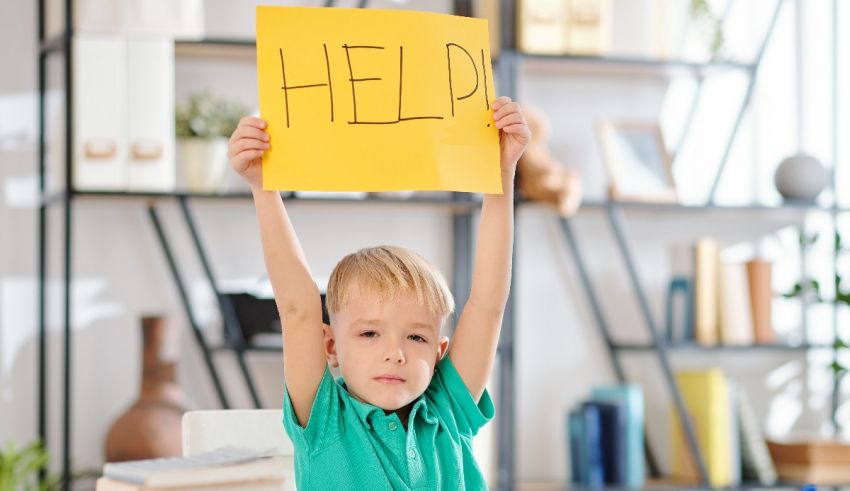 A young boy holding up a sign that says help.