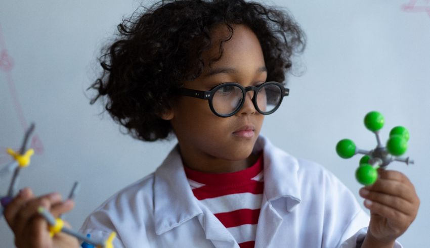 A young boy in a lab coat holding a molecule.