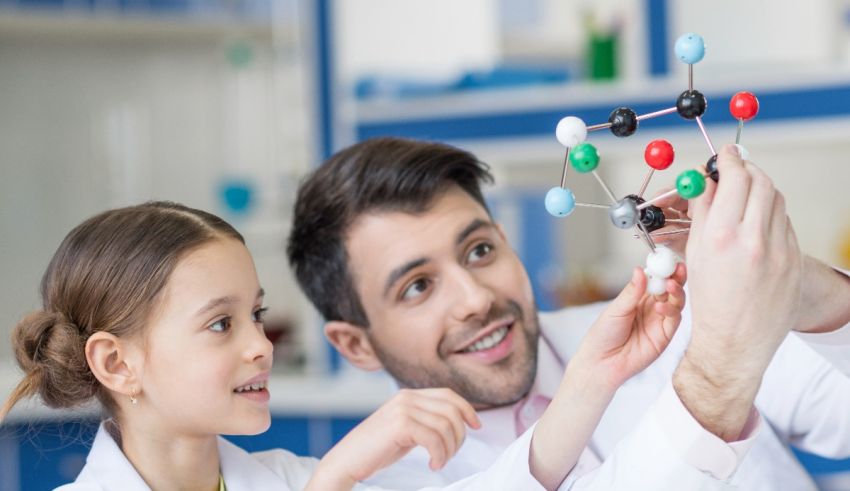 A man and a girl in lab coats looking at a molecule.