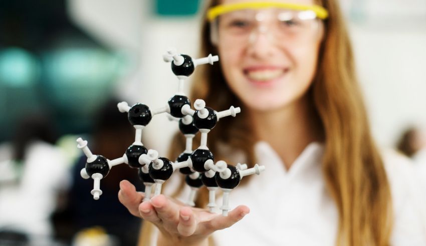 A girl holding up a model of a chemical molecule.