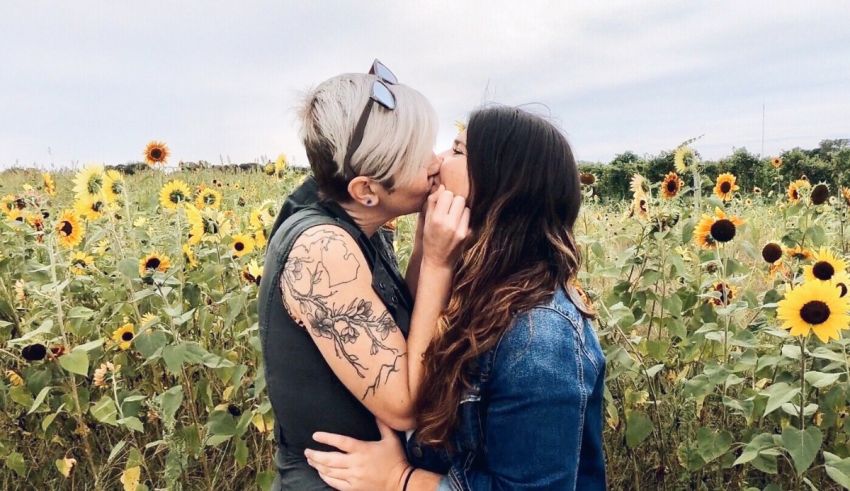 Two women kissing in a field of sunflowers.