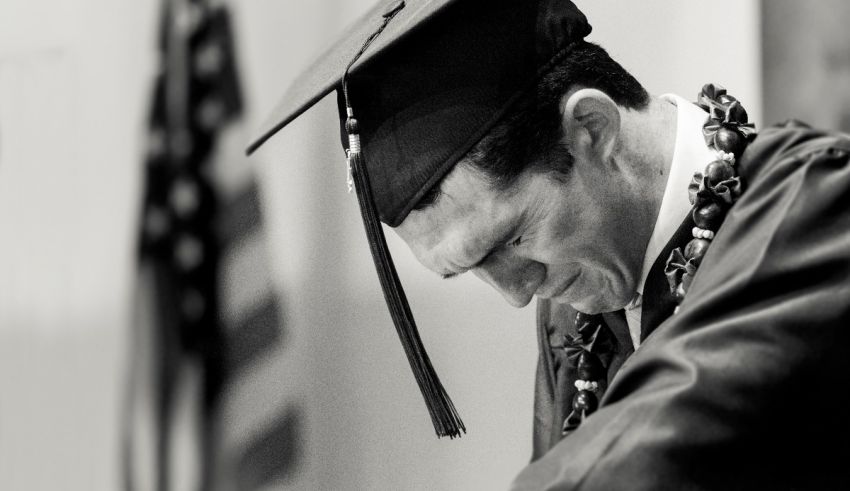 A black and white photo of a man in a graduation gown.
