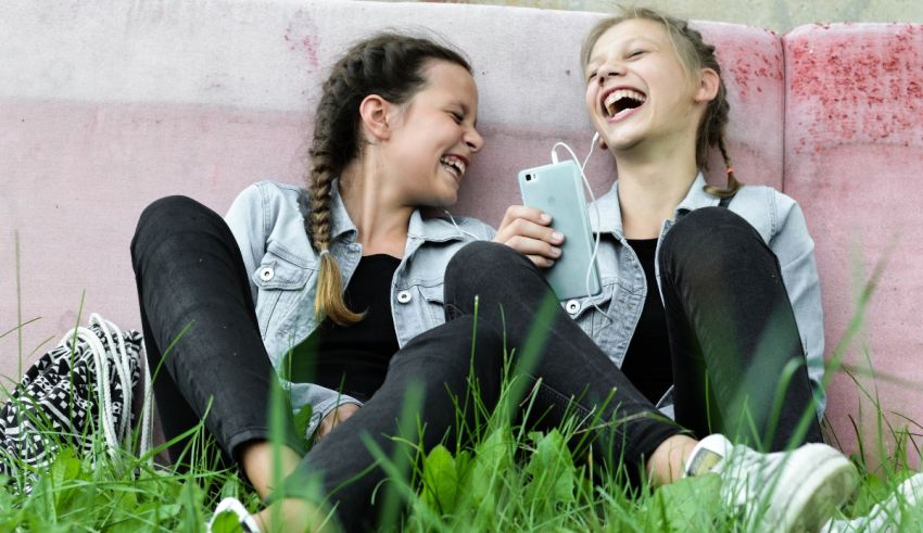 Two girls laughing while sitting in the grass.