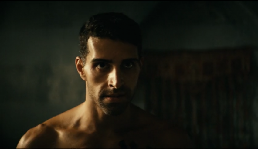 A shirtless man in a dark room.