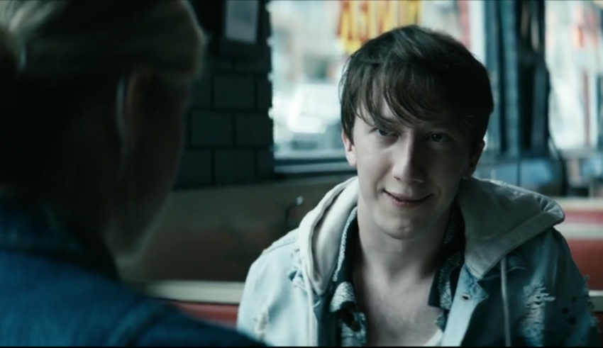 A man sitting in a diner talking to another man.