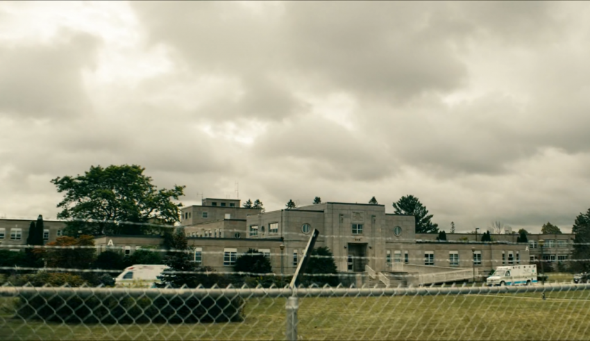 A large building with a fence and a cloudy sky.