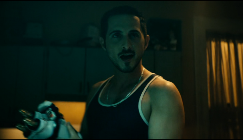 A man in a tank top standing in a kitchen.