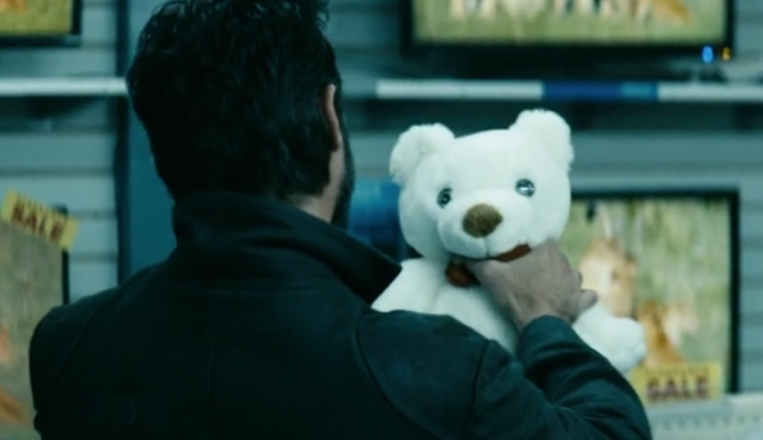 A man holding a teddy bear in a store.