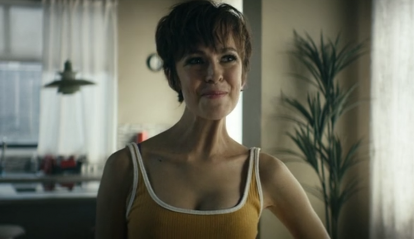 A woman in a yellow tank top standing in a room.