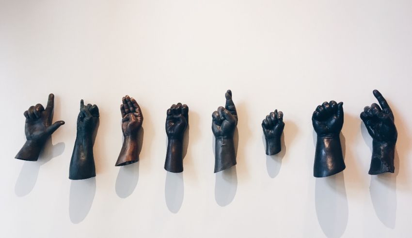 A row of black hand sculptures on a wall.