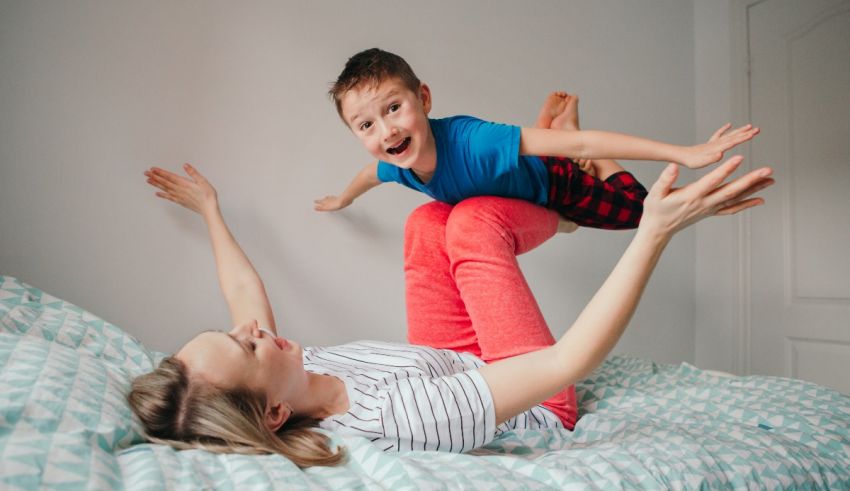 A mother and son playing on a bed.