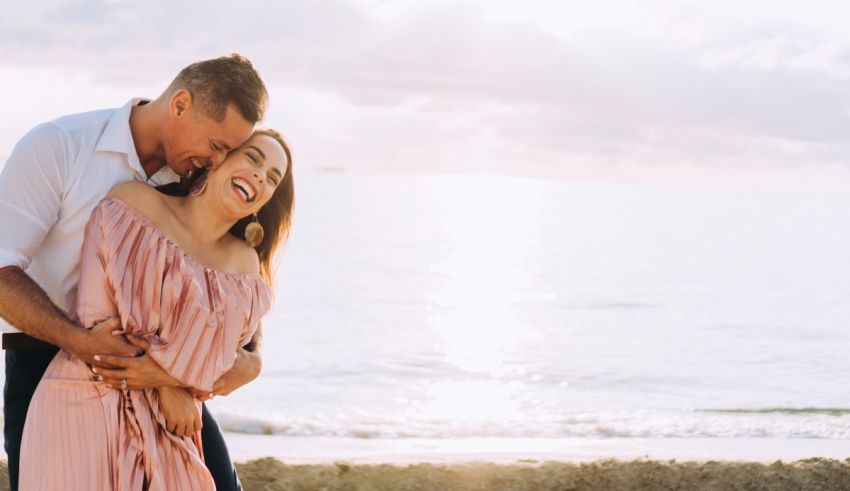 A couple hugging on the beach during their engagement session.