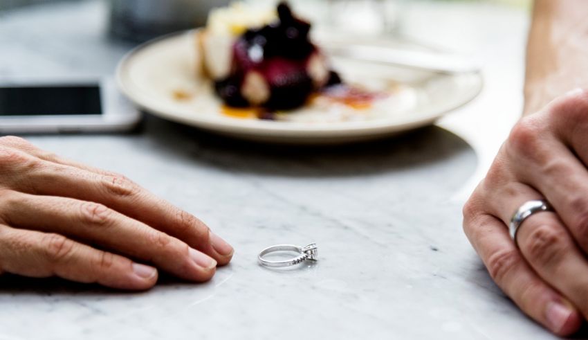 Two hands holding a wedding ring on a table.