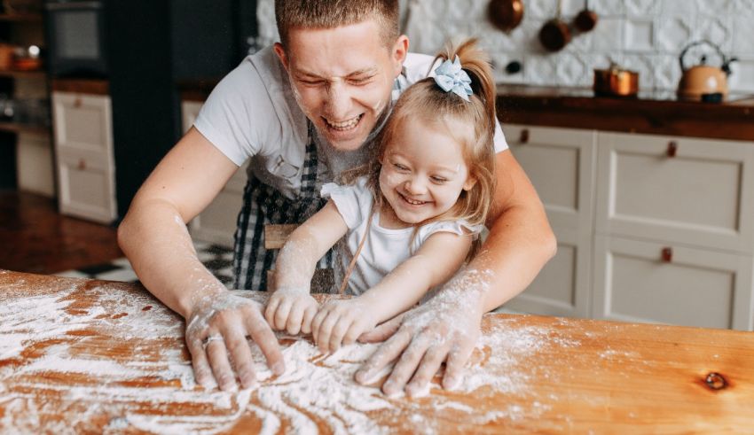 Father and daughter playing with flour in the kitchen.