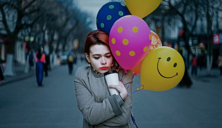 A woman holding a smiley face balloon on the street.
