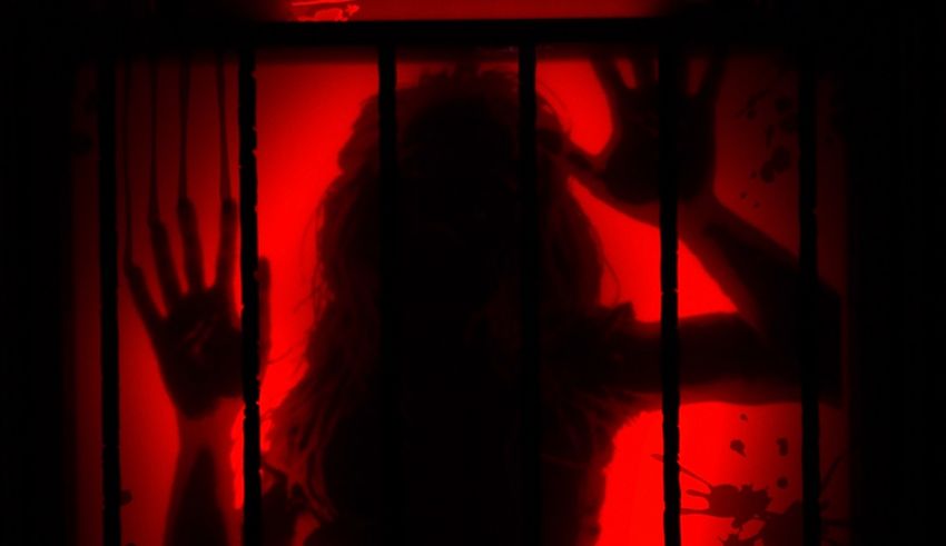 A silhouette of a woman in a cage with a red light behind her.
