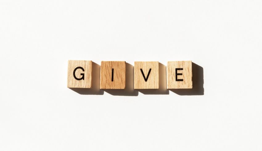 The word give spelled out in wooden blocks on a white background.