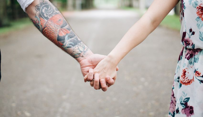 A couple holding hands with tattoos on their hands.