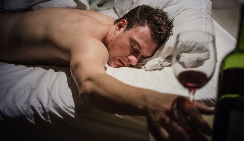 A man laying in bed with a bottle of wine.