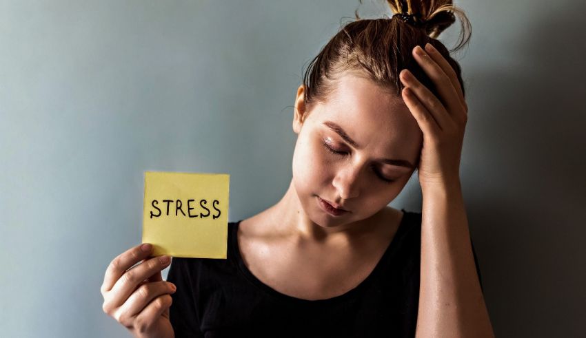 A young woman holding a note with the word stress on it.