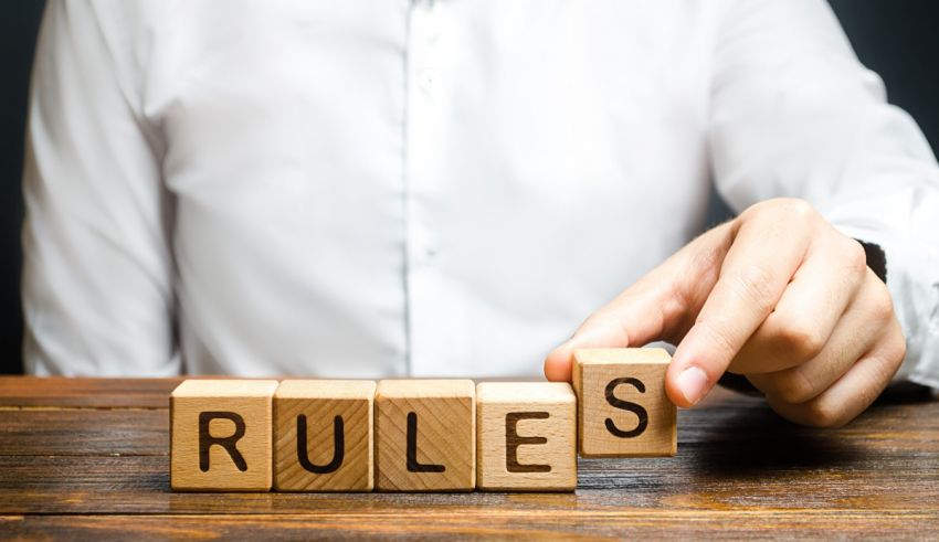 A person pointing to the word rules on wooden blocks.