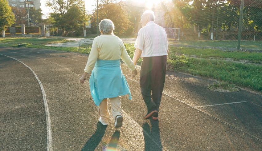 An elderly couple walking on a track in the sun.