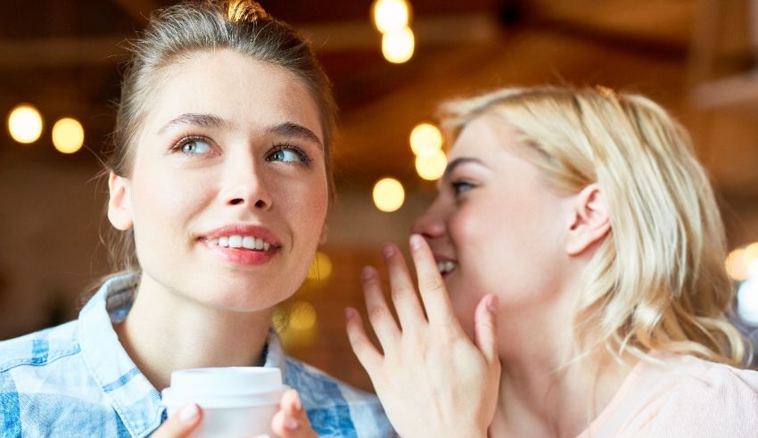 Two women whispering to each other in a cafe.