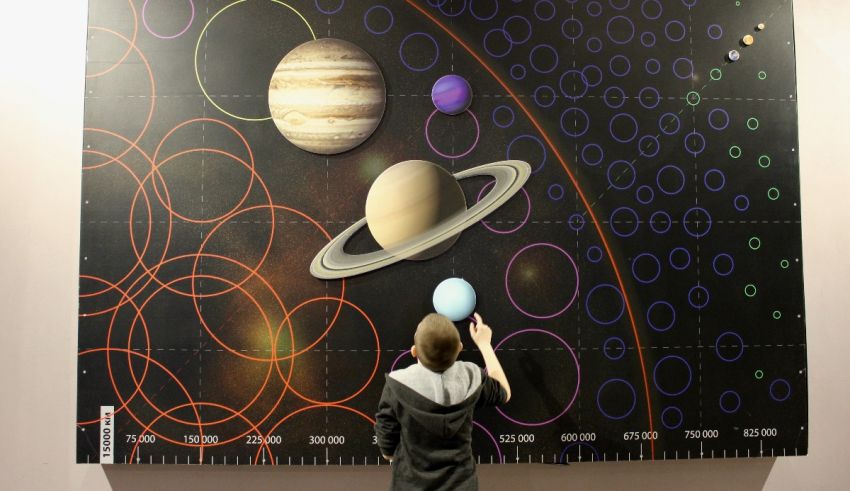 A woman standing in front of a large map of the solar system.