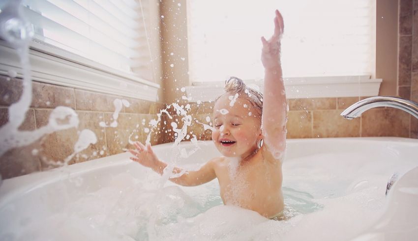 A young child playing in a bathtub with bubbles.