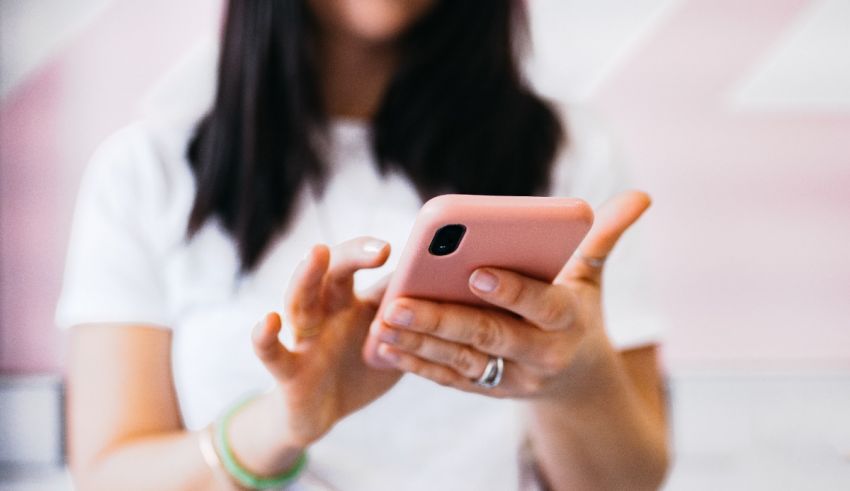 A woman holding a pink cell phone in her hand.