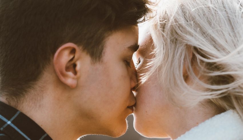 A man and woman kissing in the sun.