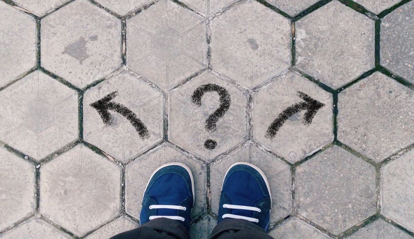 A person standing on a brick walkway with question marks drawn on it.
