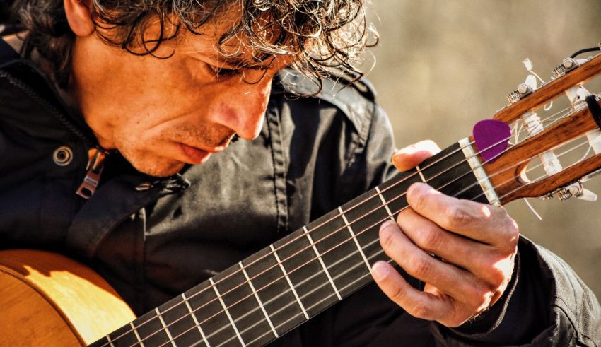 A man with curly hair playing an acoustic guitar.
