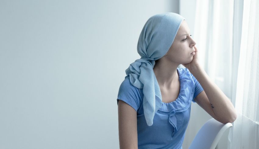 A woman sitting in front of a window with a head scarf.