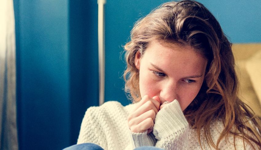 A woman sneezing while sitting on a couch.