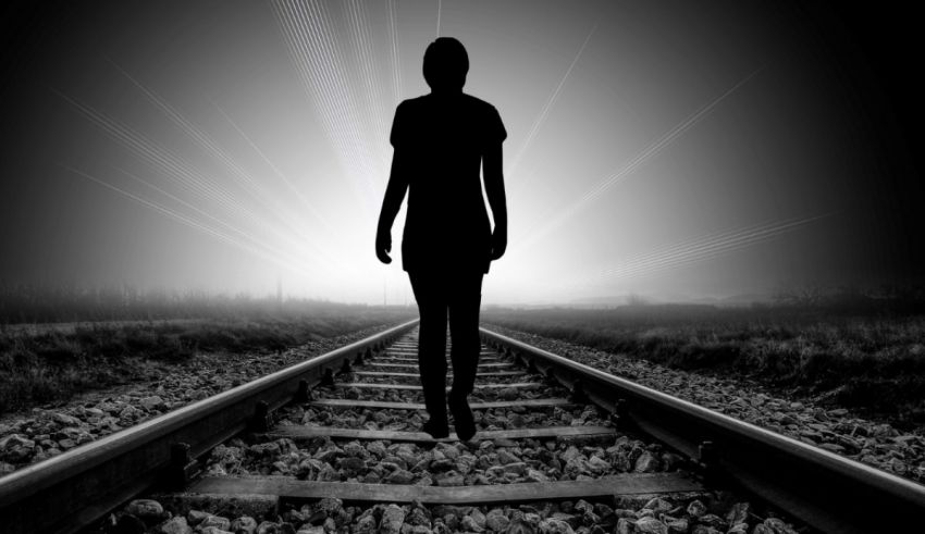 A silhouette of a woman walking on railroad tracks.