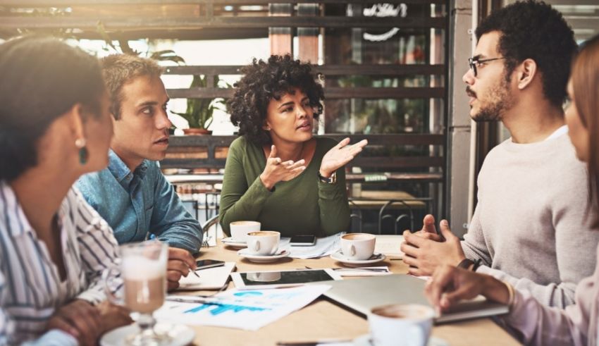 A group of people sitting around a table in a coffee shop.