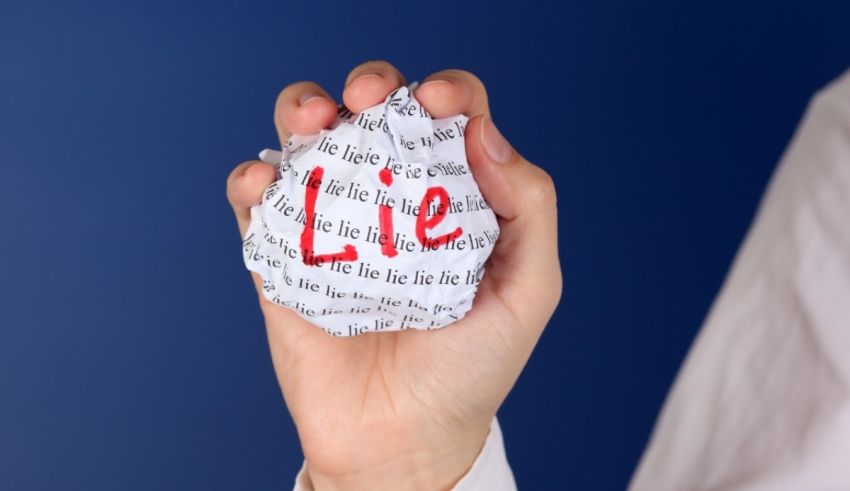 A person holding a crumpled piece of paper with the word lie written on it.