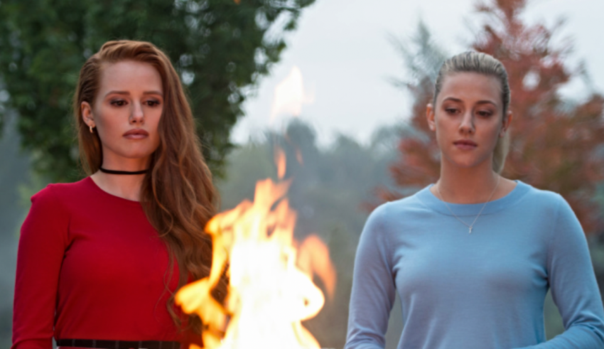 Two young women standing next to a fire.
