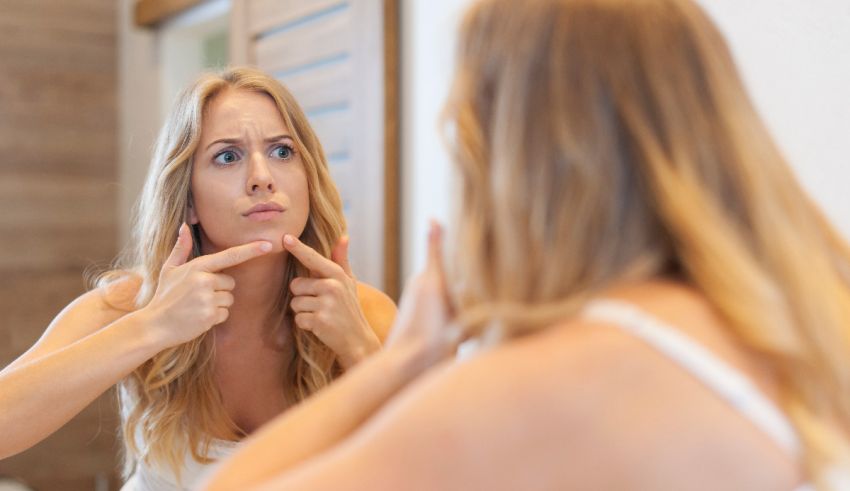 A woman is looking at her face in the mirror.