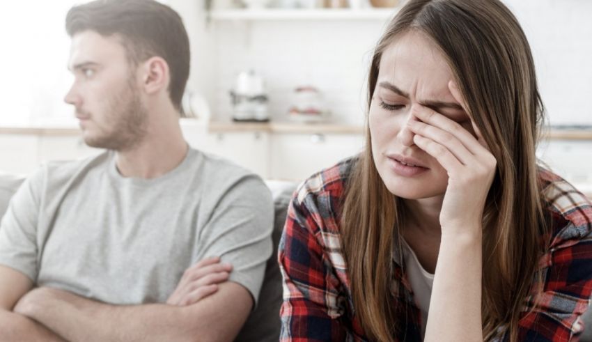 A man and woman sitting on a couch with their eyes covered.