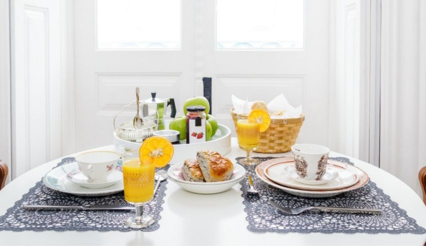 A breakfast table set with orange juice and oranges.