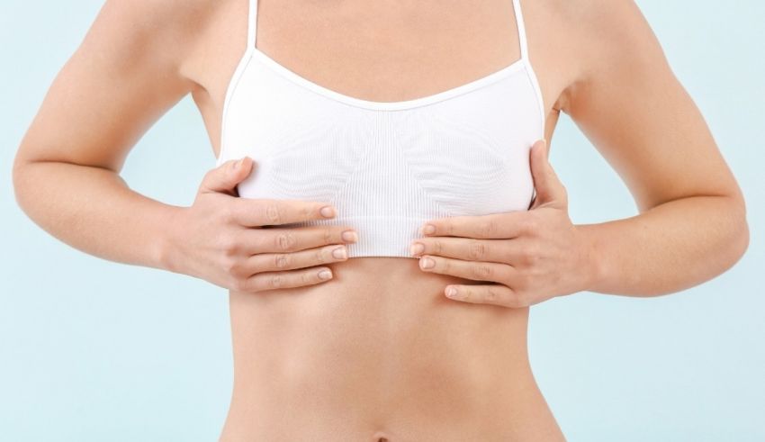 A woman in a white bra with her hands on her stomach.