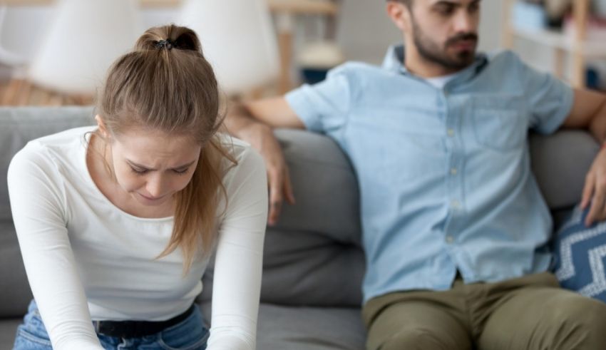 A man and woman sitting on a couch looking at a laptop.