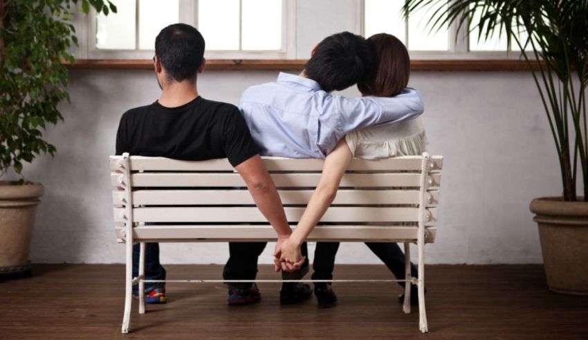 A man and woman sitting on a bench holding hands.