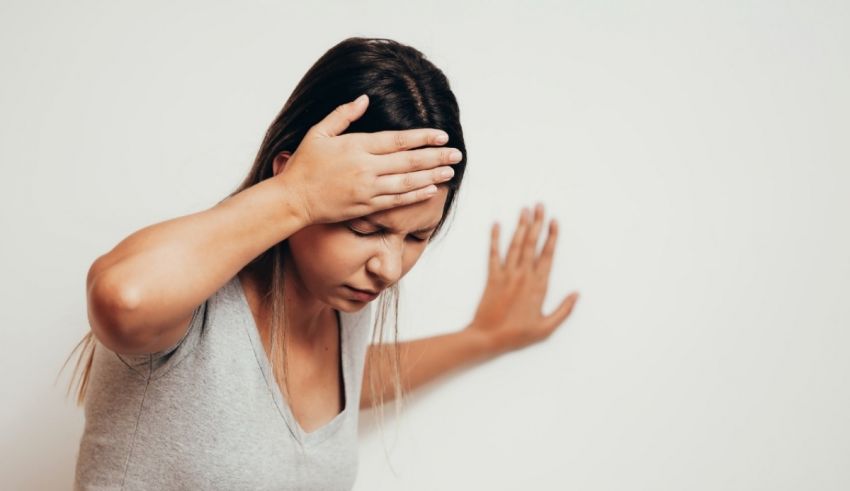 A woman with a headache is holding her hand to her head.